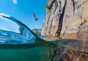Woman jumping of a cliff beside lake